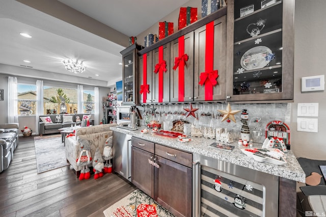 kitchen featuring dark hardwood / wood-style flooring, light stone countertops, backsplash, and beverage cooler