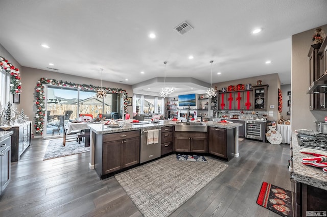 kitchen featuring light stone counters, hanging light fixtures, and beverage cooler