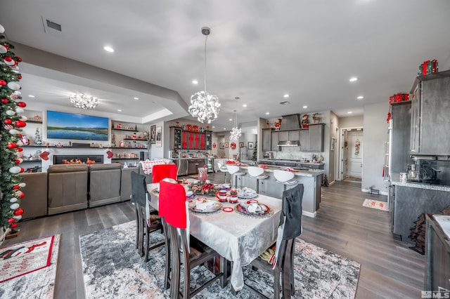 dining area with a tray ceiling, dark hardwood / wood-style flooring, and a chandelier