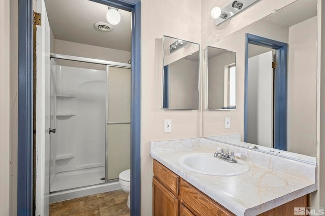 bathroom featuring toilet, vanity, and walk in shower