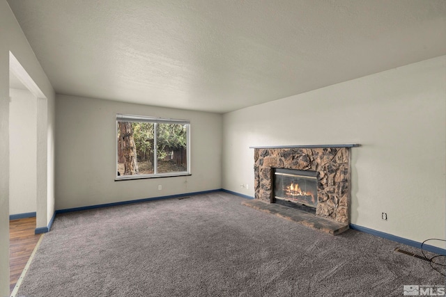 unfurnished living room with a fireplace, carpet floors, and a textured ceiling