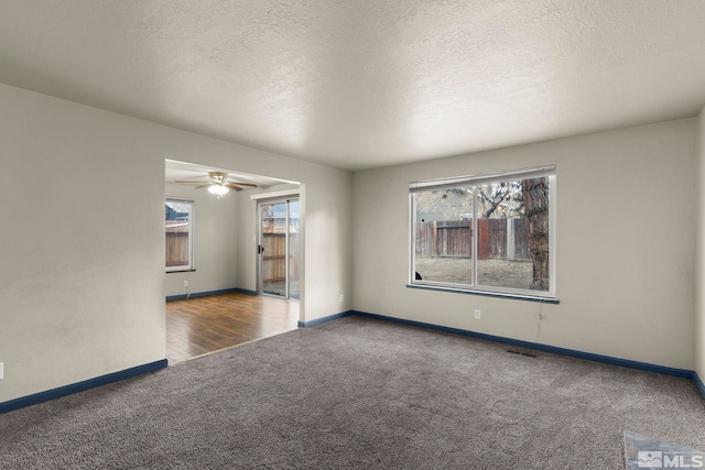 spare room featuring a wealth of natural light, a textured ceiling, and dark colored carpet