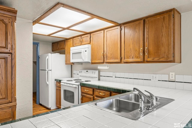 kitchen featuring tile counters, light hardwood / wood-style floors, white appliances, and sink