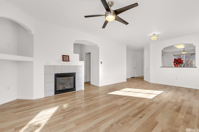 unfurnished living room with ceiling fan, light hardwood / wood-style floors, and a tile fireplace