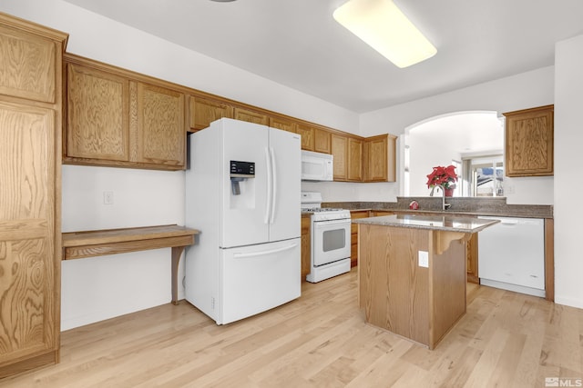 kitchen featuring sink, a kitchen breakfast bar, light hardwood / wood-style flooring, white appliances, and a kitchen island