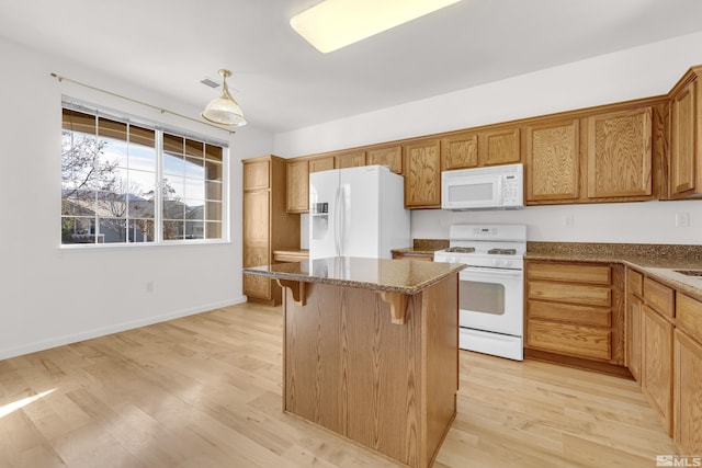 kitchen with hanging light fixtures, stone countertops, light hardwood / wood-style floors, and white appliances