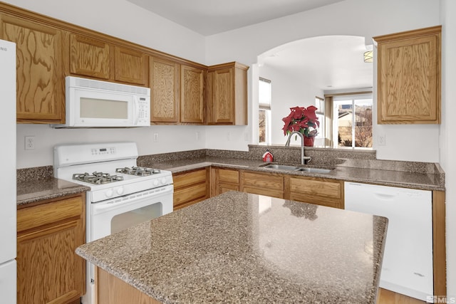 kitchen with a center island, white appliances, sink, and dark stone counters