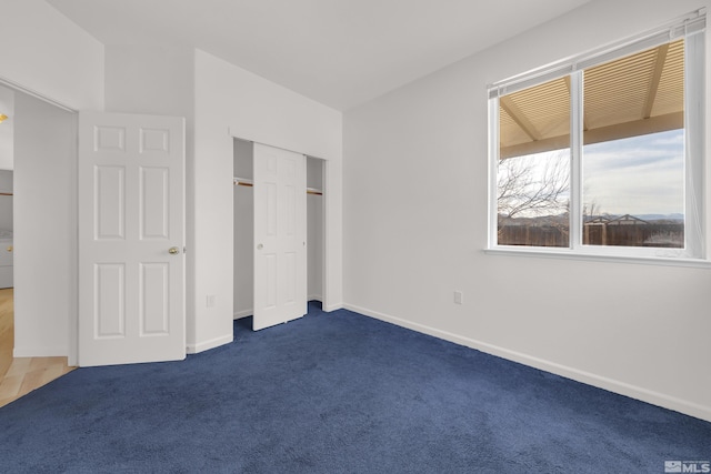 unfurnished bedroom featuring dark colored carpet and a closet