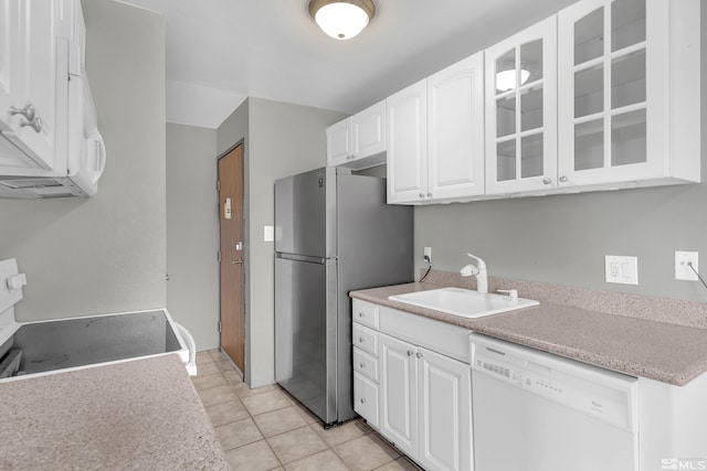 kitchen featuring sink, light tile patterned flooring, stove, white dishwasher, and white cabinets