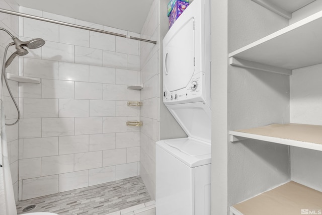 bathroom featuring tiled shower and stacked washing maching and dryer