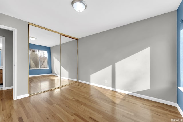 unfurnished bedroom with light wood-type flooring and a closet