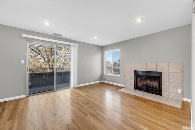 unfurnished living room with a tile fireplace and light wood-type flooring