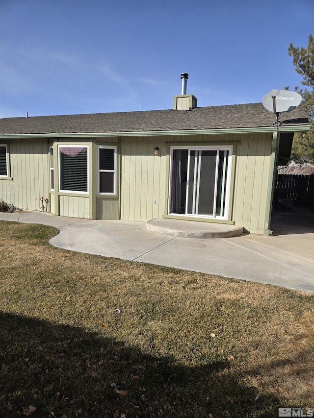 back of house with a patio area, a shingled roof, and a lawn