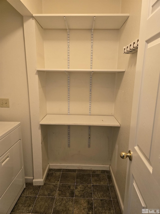 laundry area featuring laundry area, washer / clothes dryer, dark tile patterned flooring, and baseboards