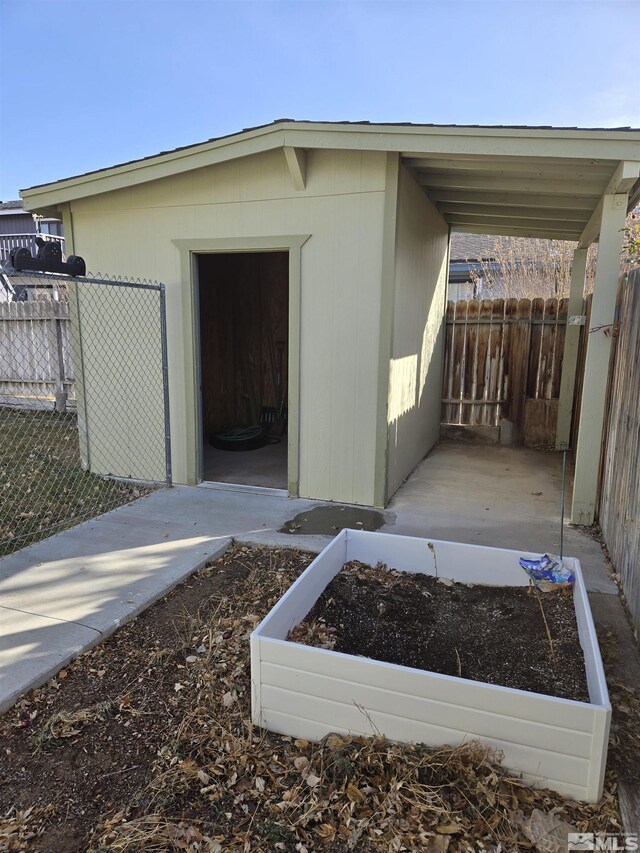 view of outdoor structure featuring a vegetable garden, fence, and an outdoor structure