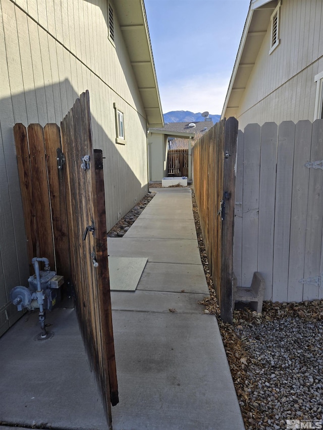 view of side of home featuring a gate, a mountain view, and fence