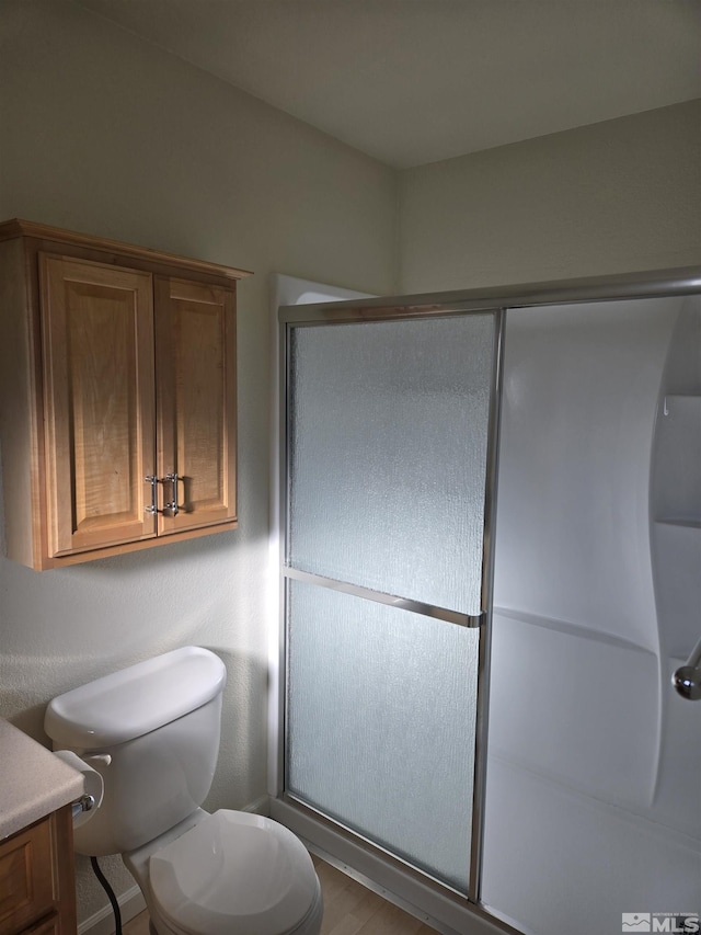 full bathroom featuring a stall shower, vanity, and toilet