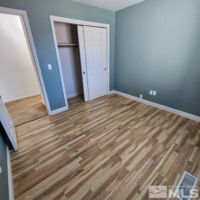 unfurnished bedroom featuring light wood finished floors, a closet, visible vents, and baseboards