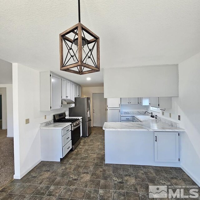 kitchen featuring appliances with stainless steel finishes, light countertops, a sink, and a peninsula