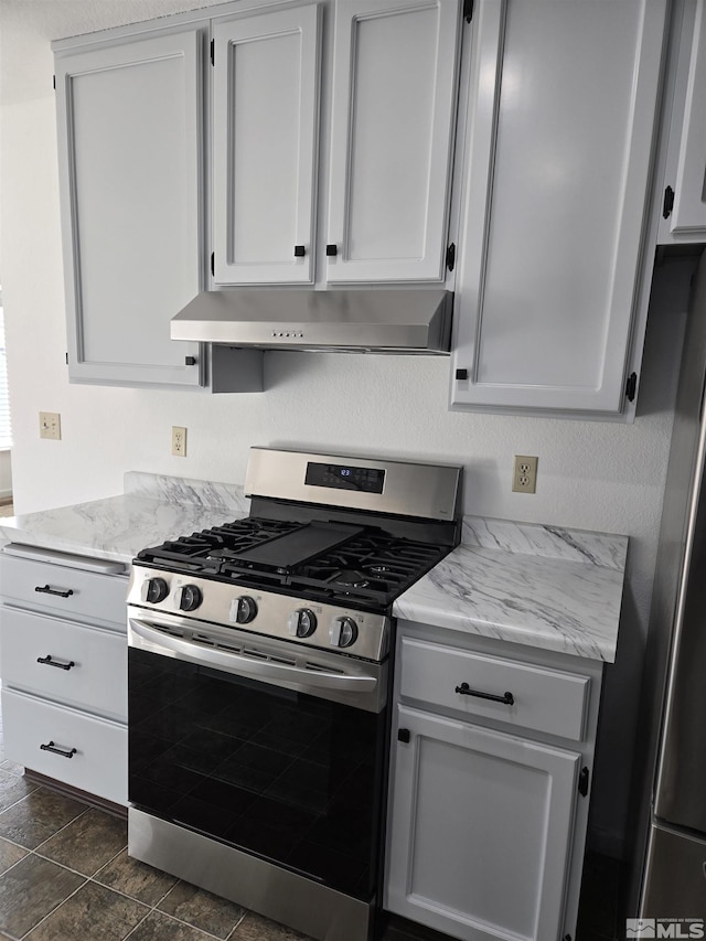 kitchen with white cabinetry, dark tile patterned floors, stainless steel appliances, and light stone counters