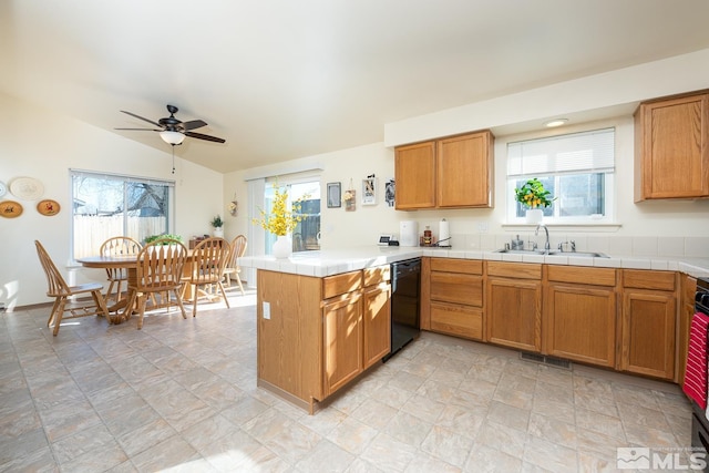 kitchen with kitchen peninsula, a wealth of natural light, sink, and black dishwasher