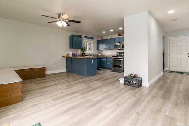 kitchen featuring kitchen peninsula, light wood-type flooring, stainless steel appliances, blue cabinets, and sink