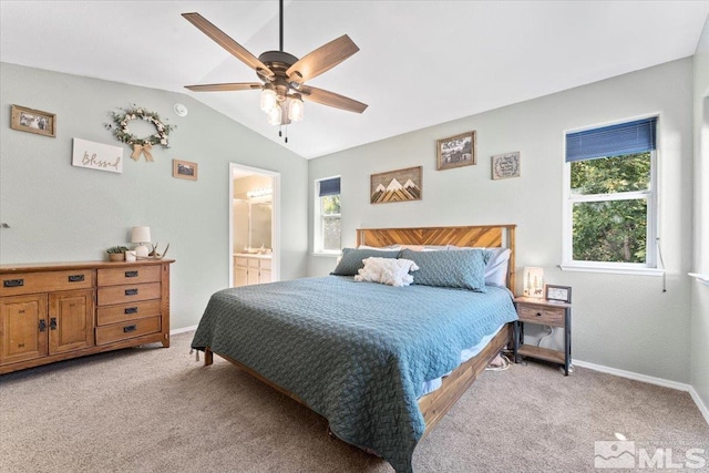 carpeted bedroom with multiple windows, vaulted ceiling, ensuite bath, and ceiling fan