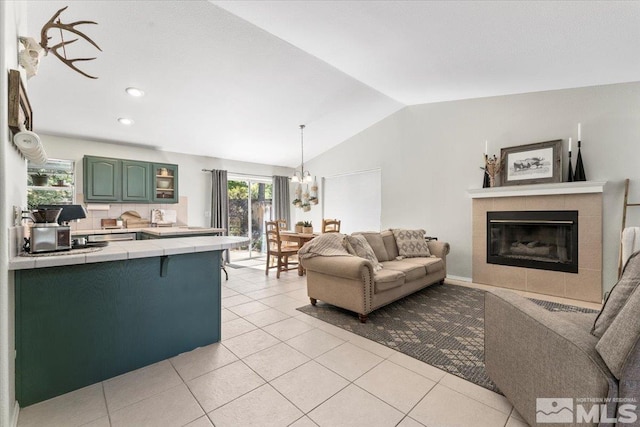 tiled living room featuring a notable chandelier, lofted ceiling, and a tiled fireplace