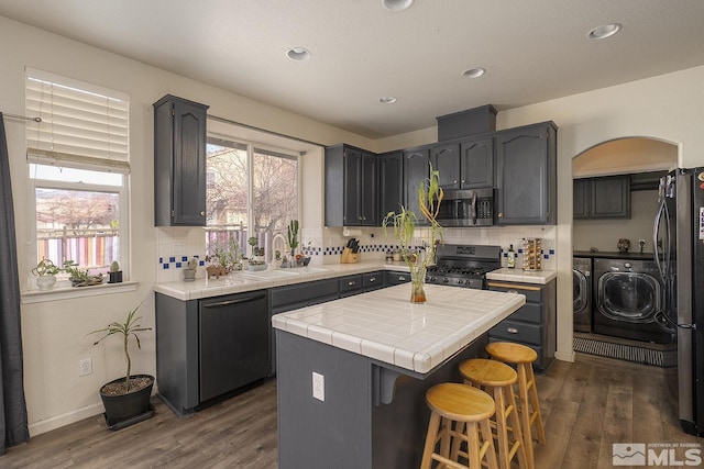 kitchen with a center island, sink, dark hardwood / wood-style floors, separate washer and dryer, and stainless steel appliances