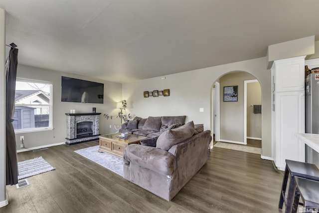 living room with a fireplace and dark wood-type flooring