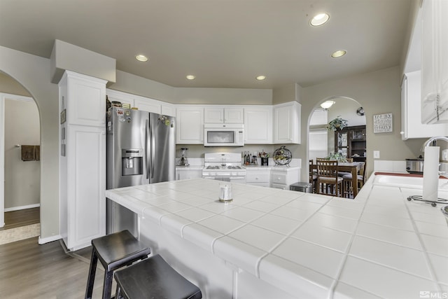 kitchen featuring tile countertops, dark hardwood / wood-style floors, white cabinetry, and white appliances