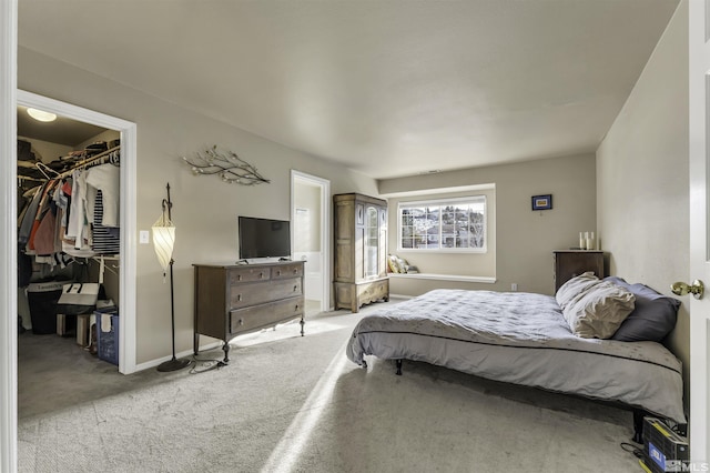 bedroom with light colored carpet, a walk in closet, and a closet