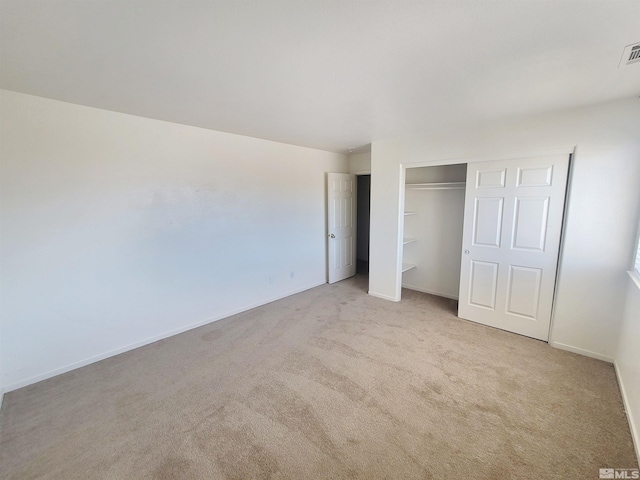 unfurnished bedroom featuring light colored carpet and a closet