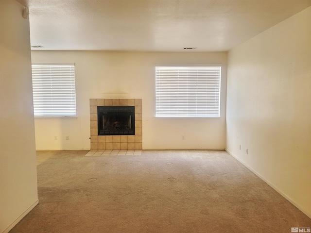 unfurnished living room featuring plenty of natural light, a fireplace, and light carpet