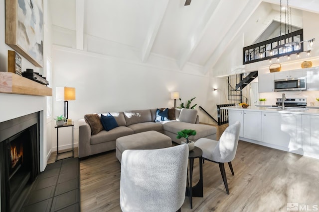 living room featuring sink, beamed ceiling, high vaulted ceiling, and hardwood / wood-style flooring