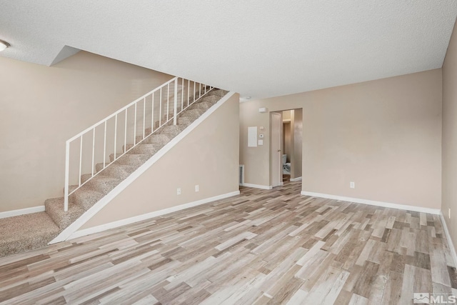 unfurnished living room with a textured ceiling and light hardwood / wood-style flooring