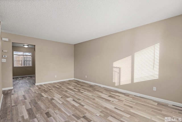 empty room featuring a textured ceiling and light hardwood / wood-style floors