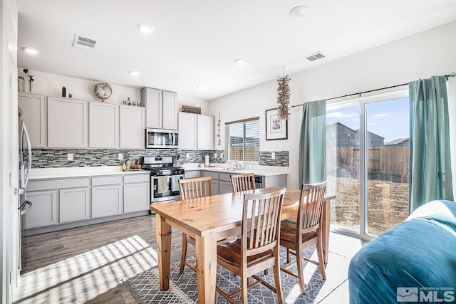 kitchen with appliances with stainless steel finishes, light hardwood / wood-style floors, a wealth of natural light, and gray cabinetry