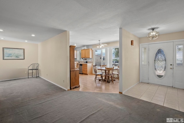 carpeted foyer entrance featuring a textured ceiling, a healthy amount of sunlight, and ceiling fan with notable chandelier