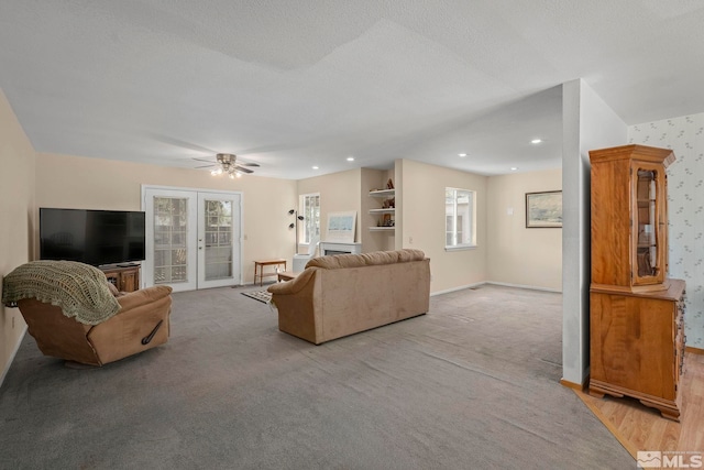 living room featuring light carpet, french doors, ceiling fan, and a textured ceiling