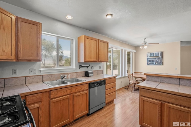 kitchen with tile countertops, black stove, dishwasher, and plenty of natural light