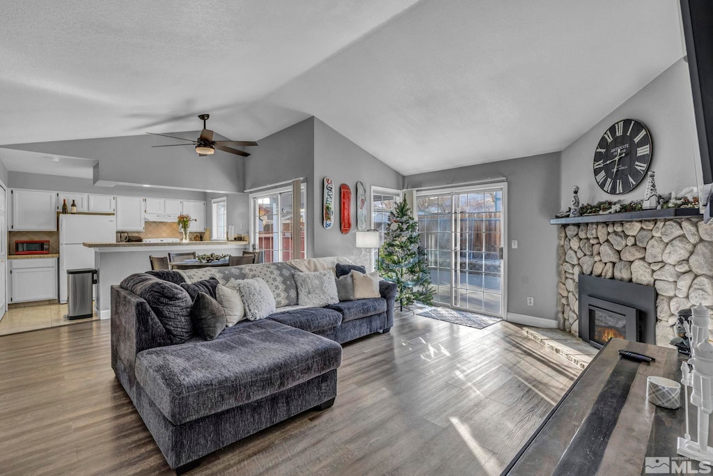 living room with ceiling fan, a fireplace, lofted ceiling, and hardwood / wood-style flooring