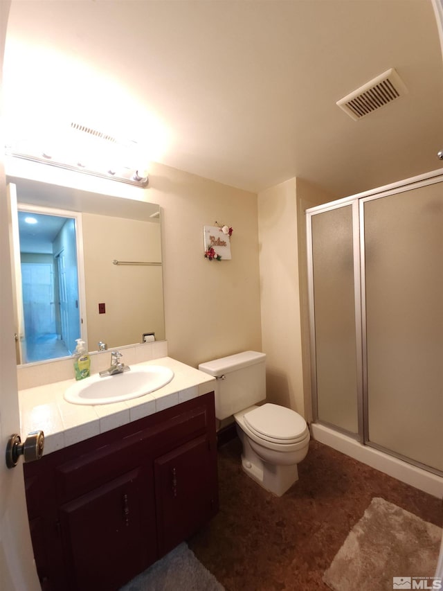 bathroom featuring vanity, toilet, and a shower with shower door