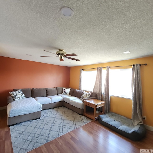 living room with ceiling fan, light hardwood / wood-style floors, and a textured ceiling