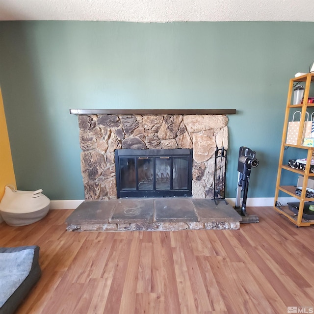 room details with a stone fireplace, a textured ceiling, and hardwood / wood-style flooring