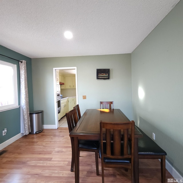 dining area with light hardwood / wood-style flooring and a textured ceiling