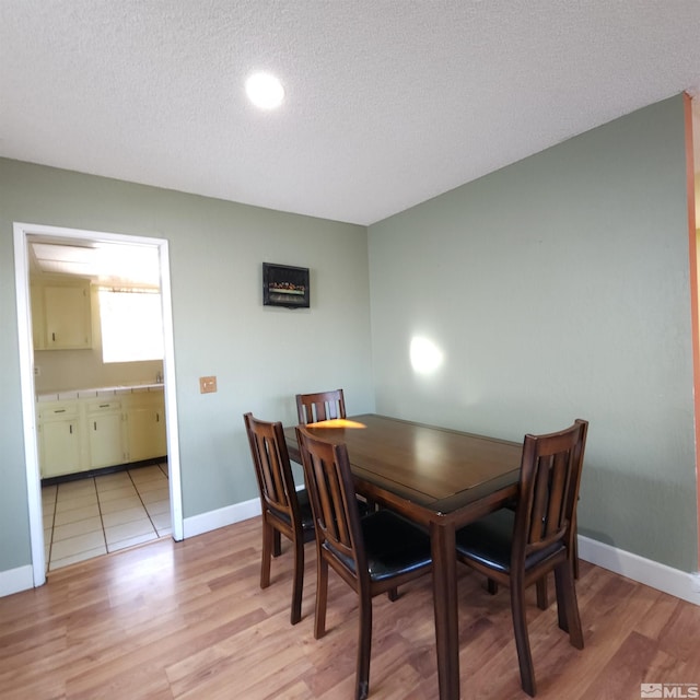 dining area with a textured ceiling and light hardwood / wood-style flooring