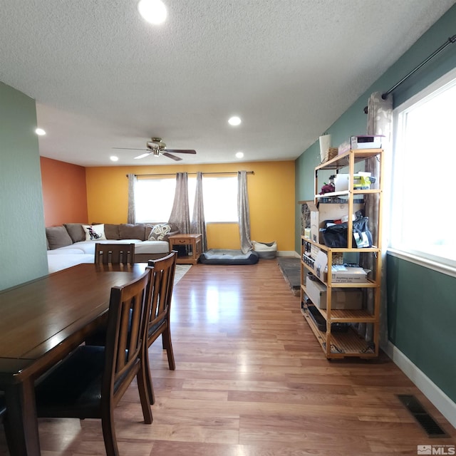 dining room with hardwood / wood-style flooring, ceiling fan, and a textured ceiling