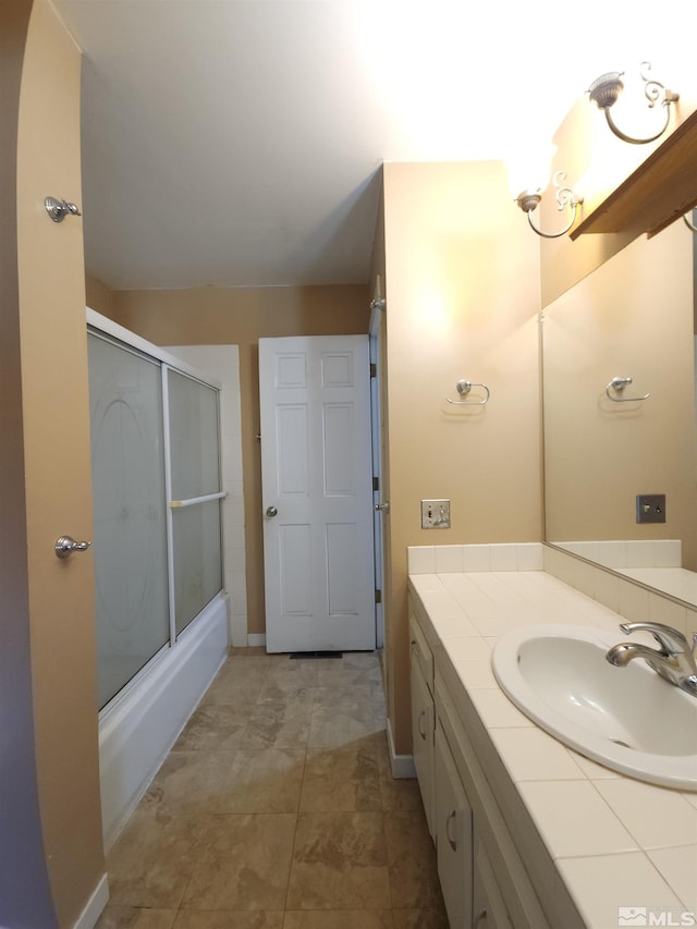 bathroom featuring tile patterned flooring, vanity, and bath / shower combo with glass door