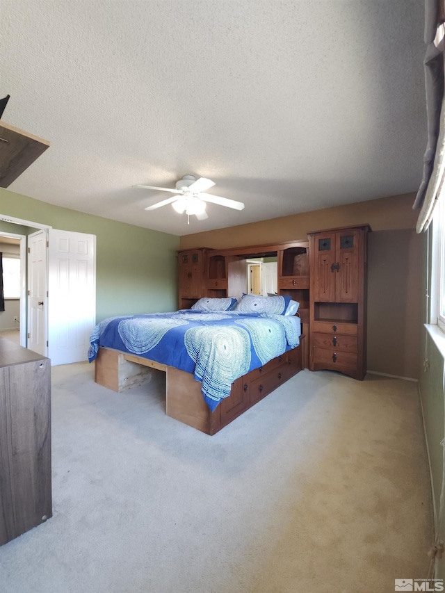 carpeted bedroom with ceiling fan and a textured ceiling